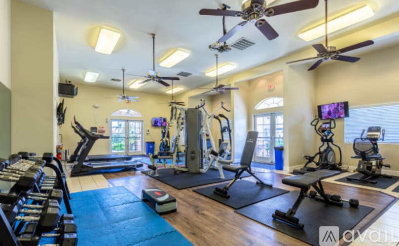 A well-equipped gym with various exercise machines and a television.