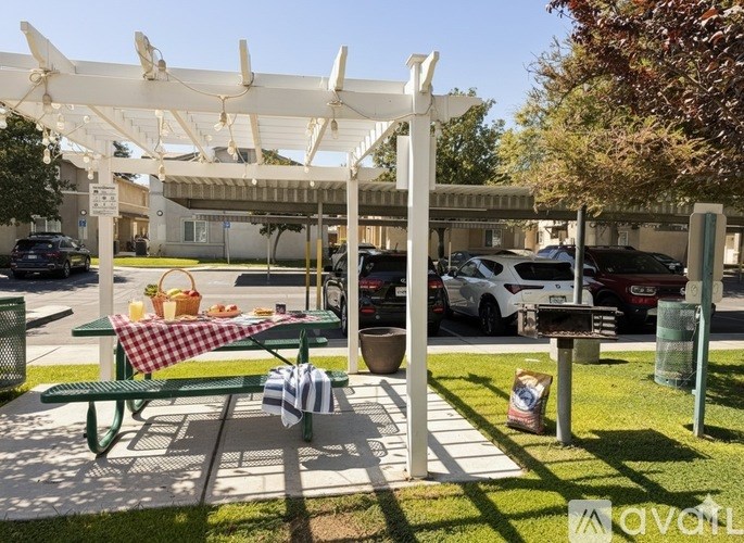 A picnic table is set up under a white canopy in a parking lot.