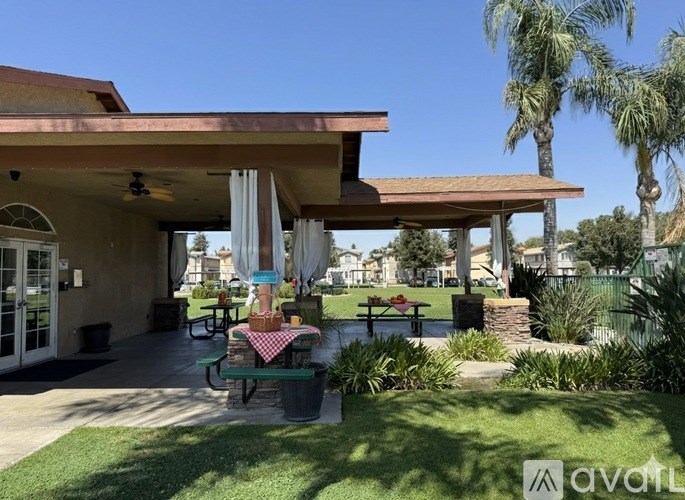 A patio area with a table and chairs under a roof.