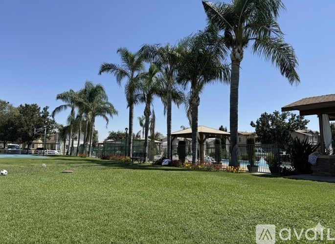 A grassy area with palm trees and a building in the background.