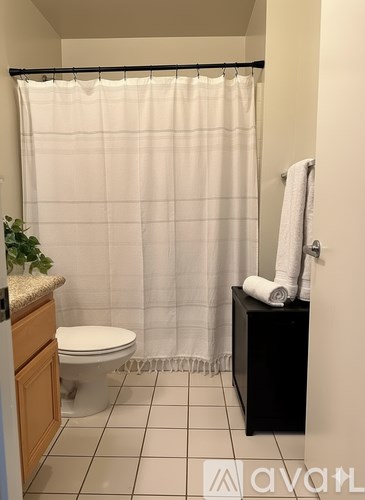 A bathroom with a toilet, a shower curtain, and a towel.