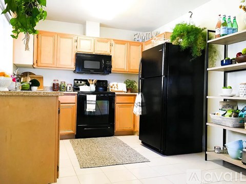 A kitchen with a black refrigerator and wooden cabinets.