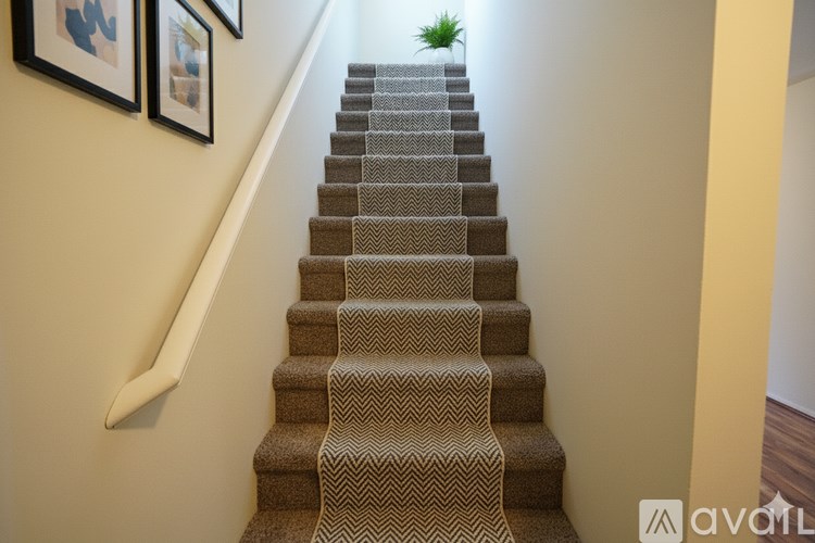 A staircase with a carpeted runner and a wooden handrail.