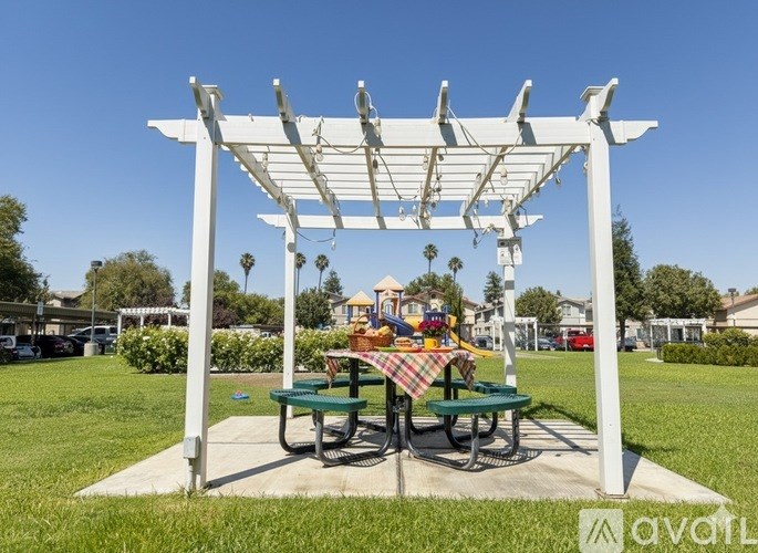 A white pergola with a picnic table underneath it.
