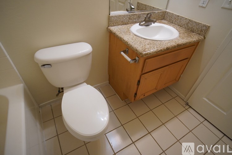 A bathroom with a toilet, sink, and tiled floor.