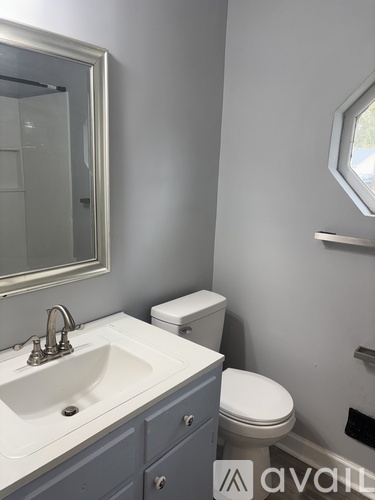 A bathroom with a sink, toilet and mirror.