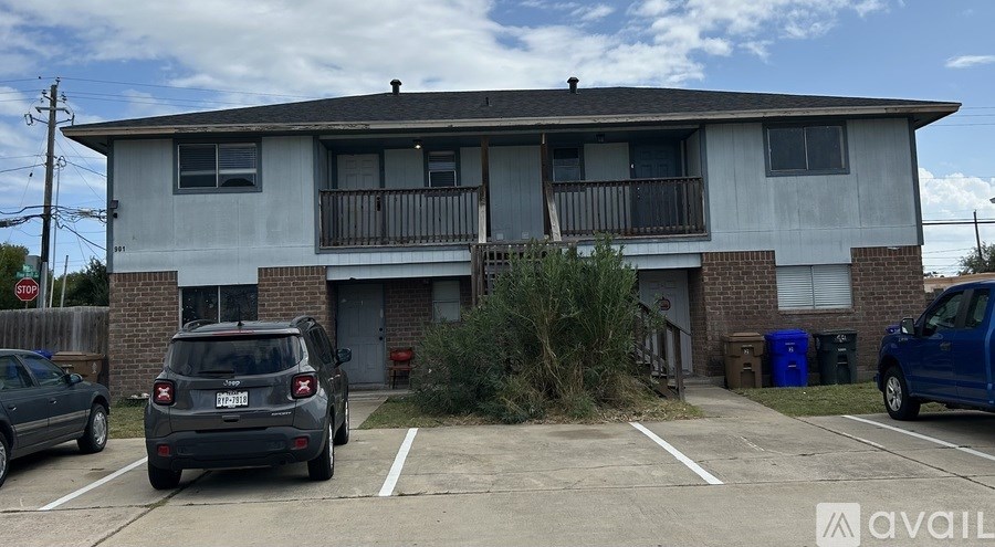 A grey apartment building with a car parked in front.