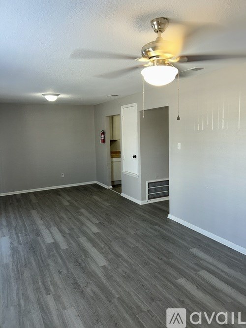 A room with a ceiling fan and light fixture, and a wooden floor.