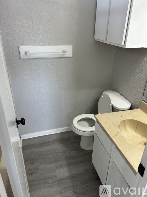 A bathroom with a toilet, sink, and a white cabinet.