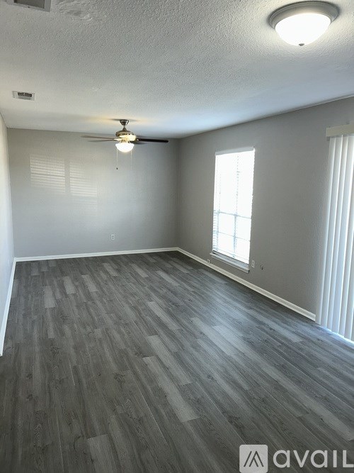 A room with a ceiling fan and a window with blinds.