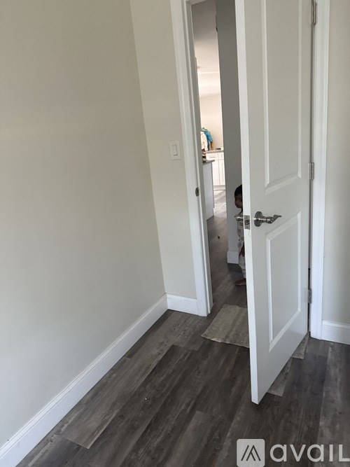 A hallway with a white door and a person standing in the doorway.