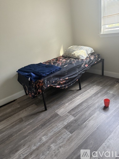 A bed with a floral comforter and a red cup on the floor.