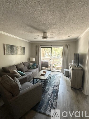 A living room with a grey couch and a painting on the wall.