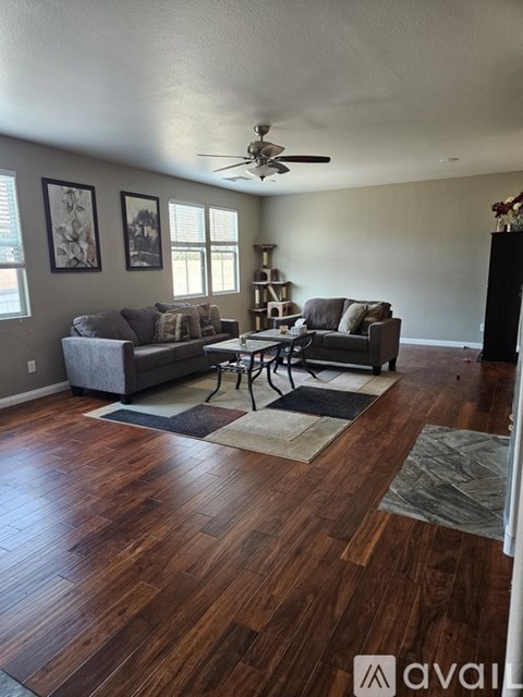 A living room with a grey couch and a wooden floor.