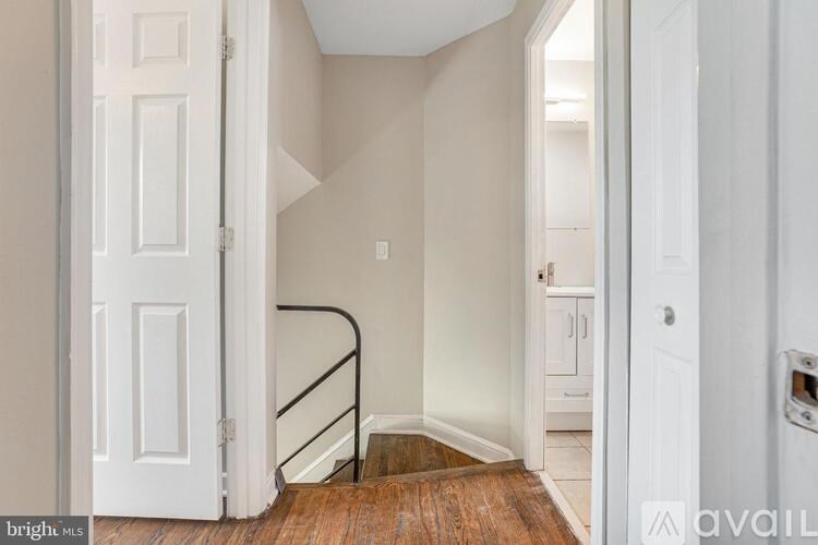 A hallway with a wooden floor and white walls.