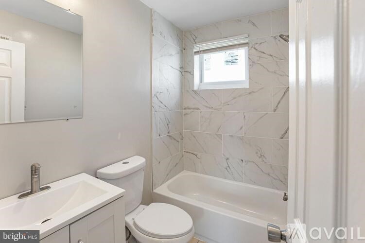 A white bathroom with a marble wall and a toilet.