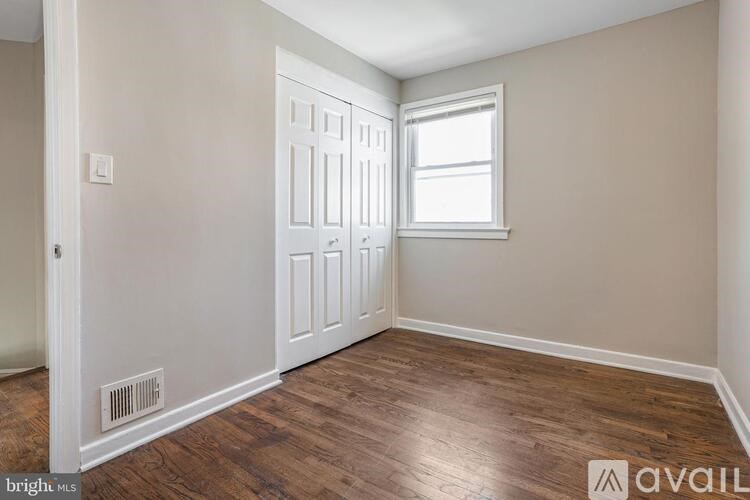 A room with a white door, a window, and a wooden floor.