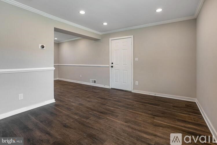 A room with a white door and wooden flooring.