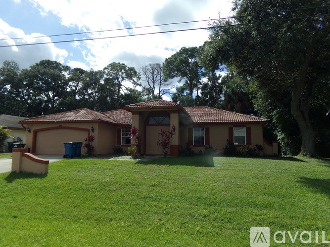 A house with a red tiled roof and a green lawn in front.