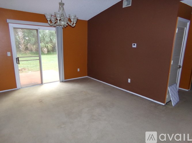 A room with a chandelier and sliding glass doors.