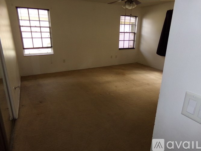 A room with a ceiling fan and two windows.