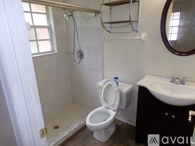A white toilet in a small bathroom with a sink and mirror.