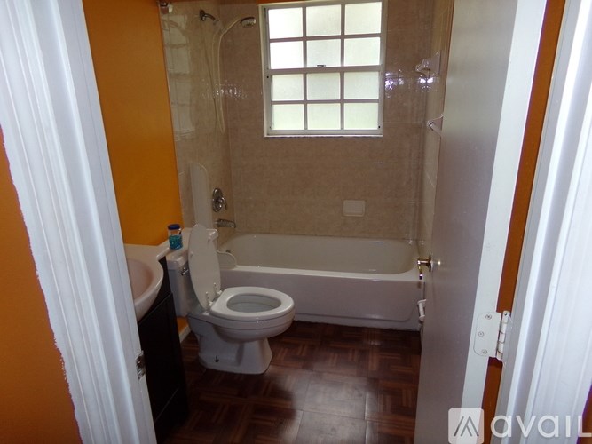 A bathroom with a toilet, tub, and window.