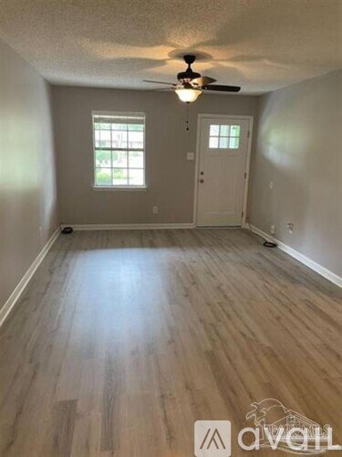 A room with a ceiling fan and wooden flooring.