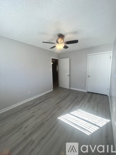 A room with a ceiling fan and light, and a wooden floor.