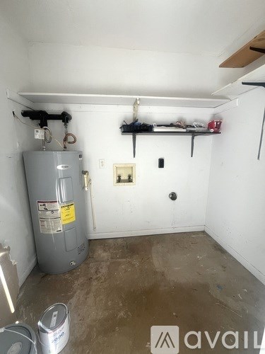 A room with a grey water heater and a white wall.