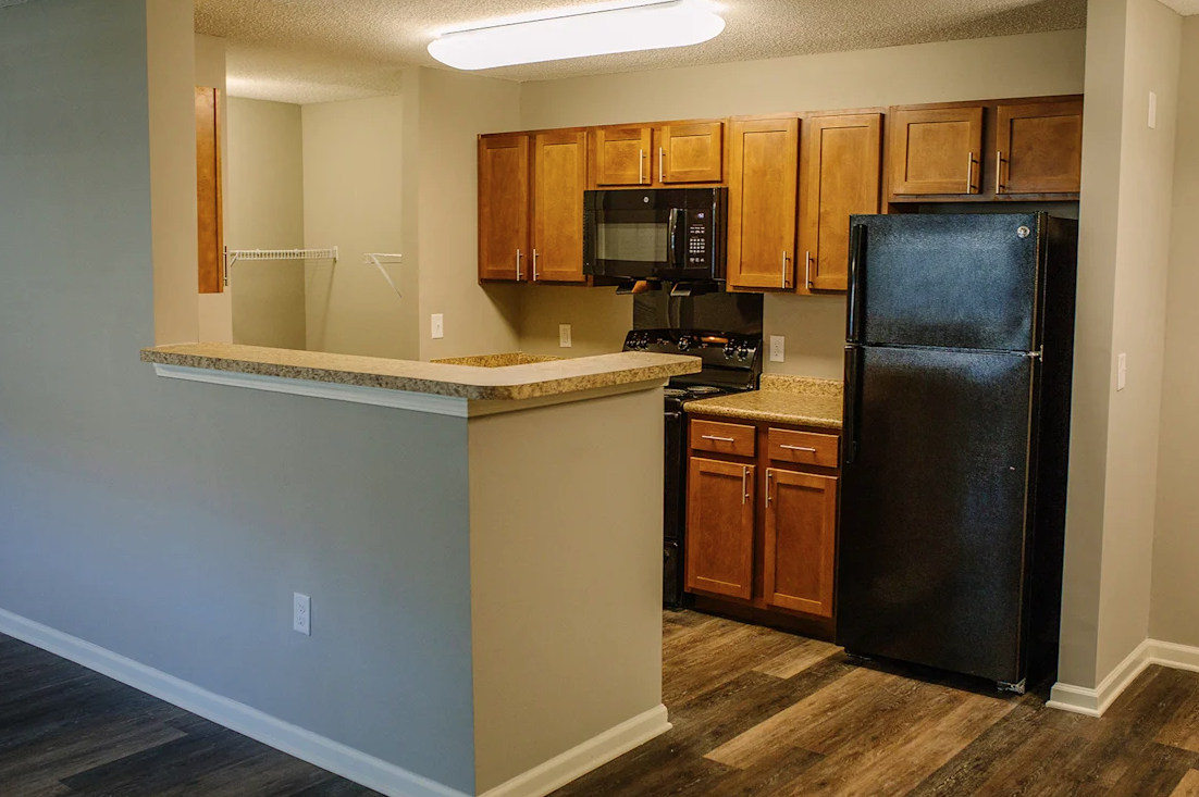 A kitchen with wooden cabinets and a black refrigerator.