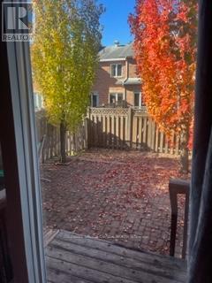 A view of a backyard through a window with a wooden fence and trees.