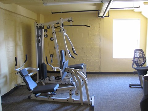 A gym with a weight bench, a cable machine and a window.