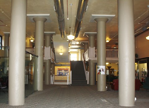 A hallway with a staircase and a glass wall on the left.