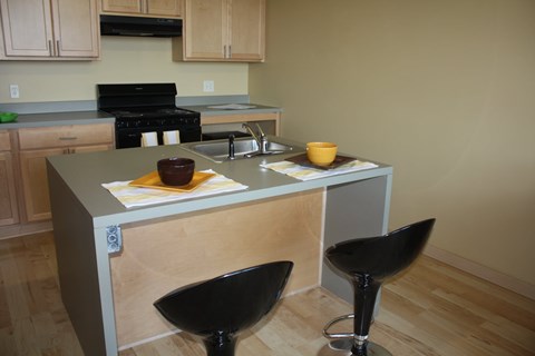 A kitchen with a black stove top oven and a black chair.