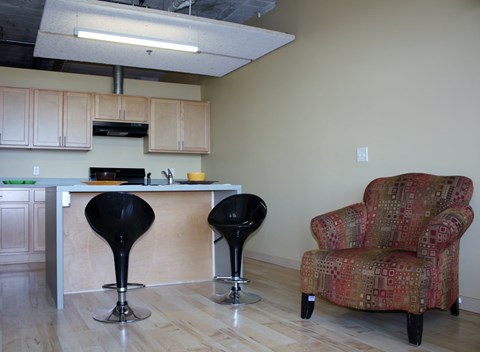 A kitchen with a bar and two chairs.