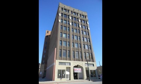 A tall building with a red sign on the ground floor.