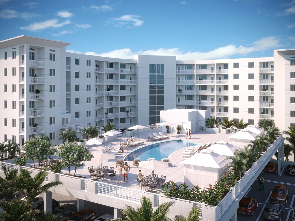 A large white hotel with a pool and people enjoying the sun.
