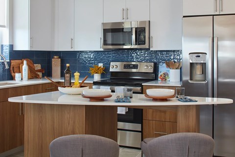 A modern kitchen with a white countertop and stainless steel appliances.