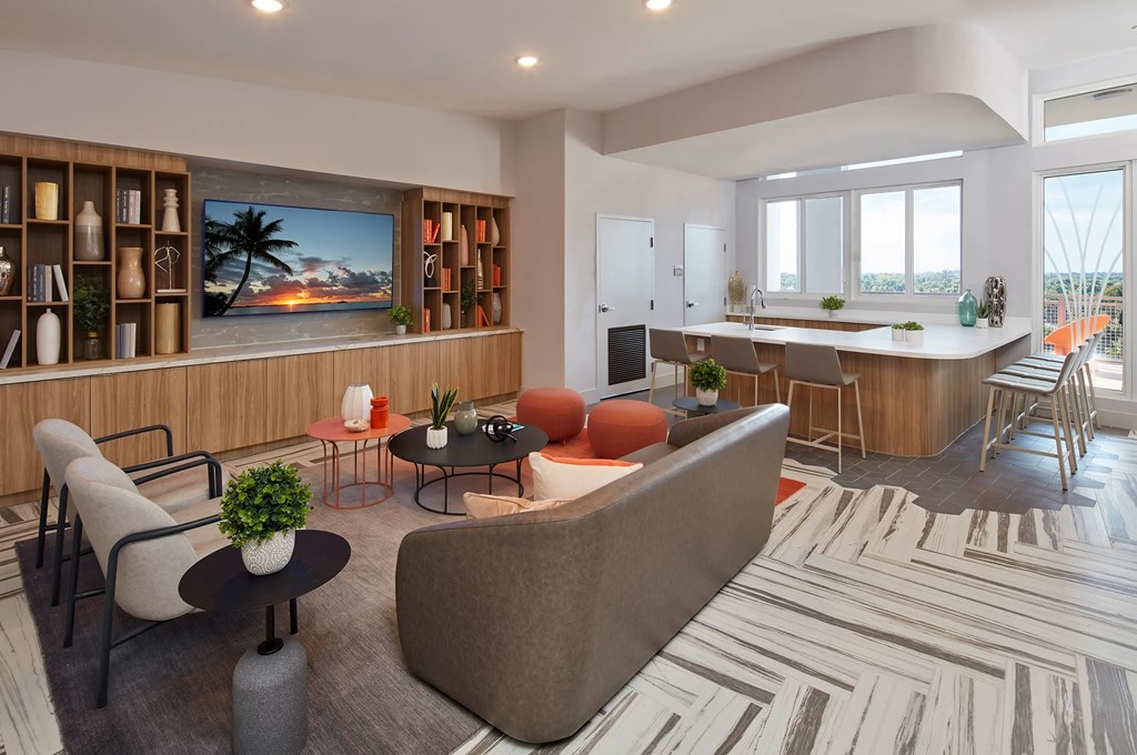 A modern living room with a large couch, a TV, and a kitchen area in the background.