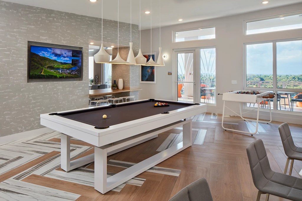 A pool table in a room with a television and a view of the outdoors.
