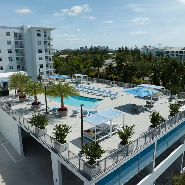 A large white building with a pool and palm trees.
