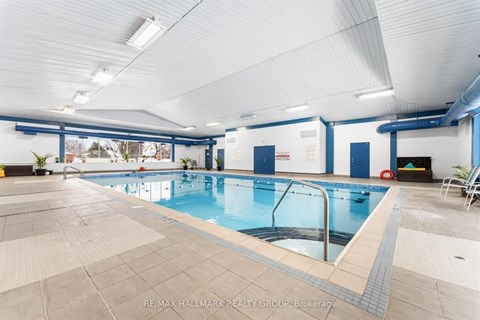 A large indoor swimming pool with a blue tiled edge and a glass divider.
