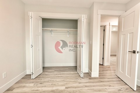 A room with a white door and a Rodman Realty Inc. logo on the wall.