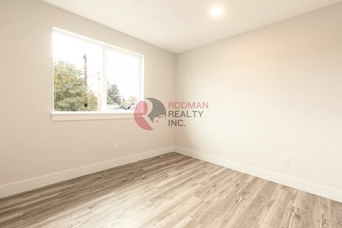 A room with a window and a wooden floor.