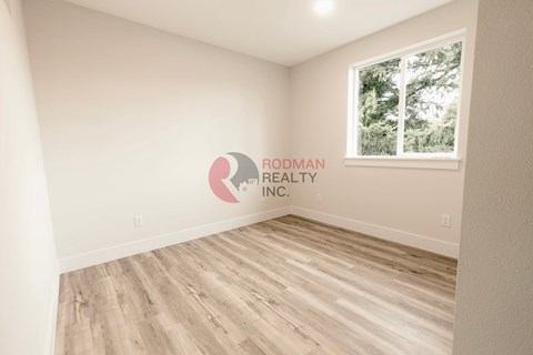 A room with a window and a logo of Rodman Realty Inc. on the wall.