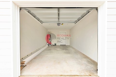 A white garage door with a sign that says "Rodman Realty Inc." on it.