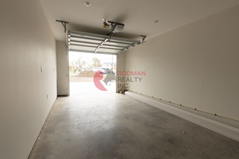 A large empty room with a sign that says "Rodman Realty Inc." on the wall.