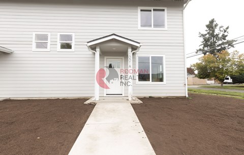 A house with a sign that says "Rodman Real Estate Inc." in front of it.