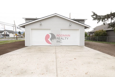 A two-car garage with a sign that says Rodman Realty Inc.